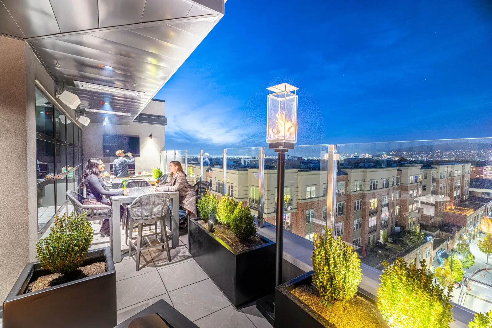 Residents dining on the Sugar Alley rooftop at dusk with the city beyond