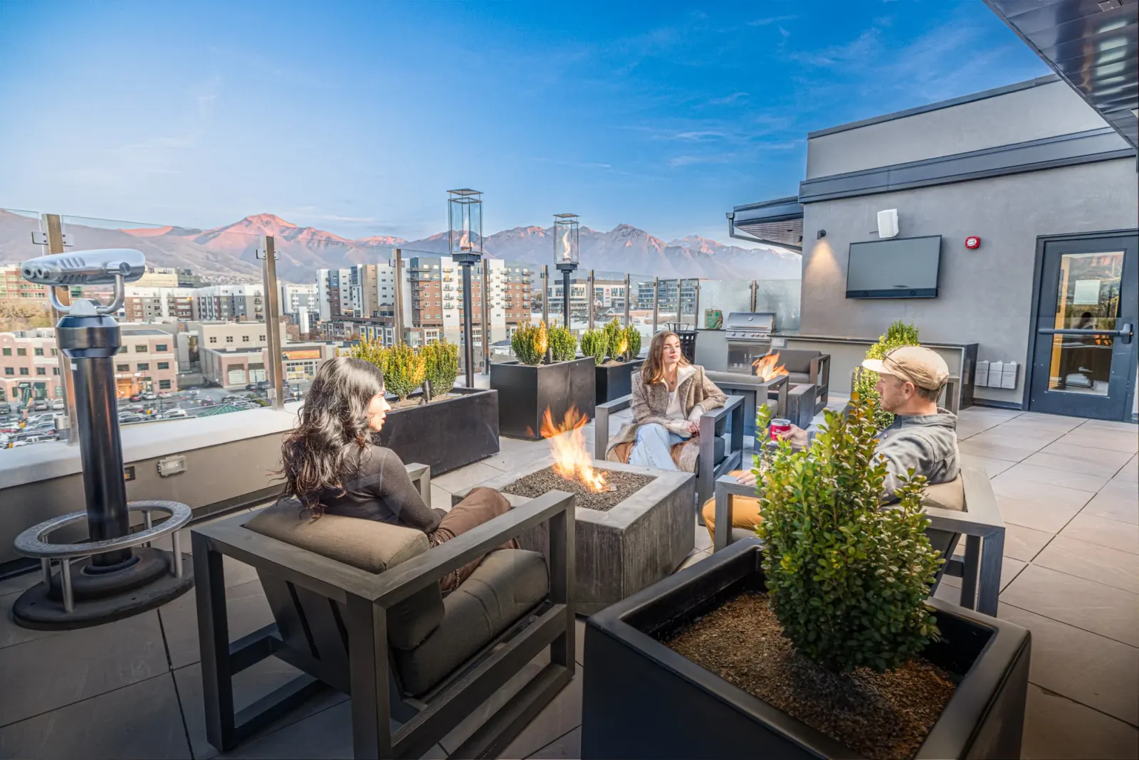 Residents around the Sugar Alley rooftop fire lounge with the mountains beyond